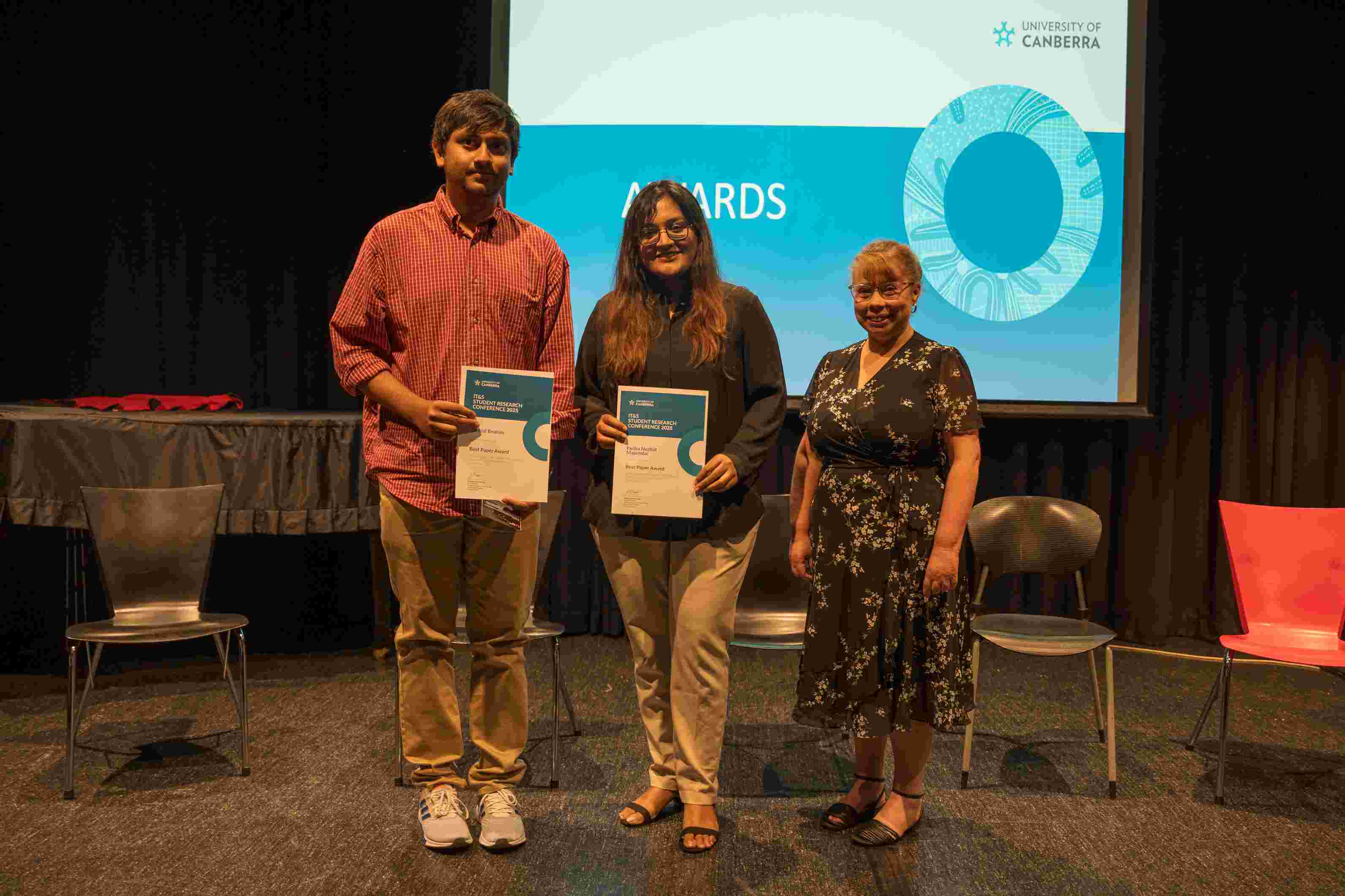 Two people holding an award certificate and smiling for the camera.