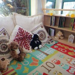 a comfortable area with cushions, teddies, books 
